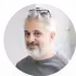 Smiling person with glasses and gray hair.