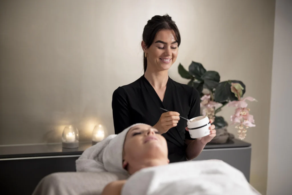 Woman applying facial treatment in spa setting