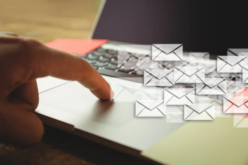 Finger tapping laptop with floating email icons