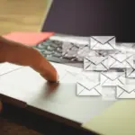 Finger tapping laptop with floating email icons